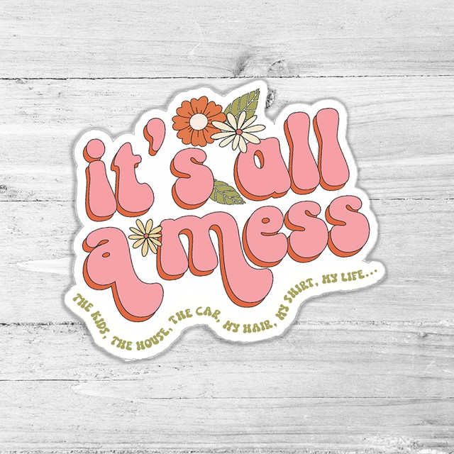 It's All A Mess Die Cut Sticker, decorative sticker with pink text and floral design on a light wooden background.