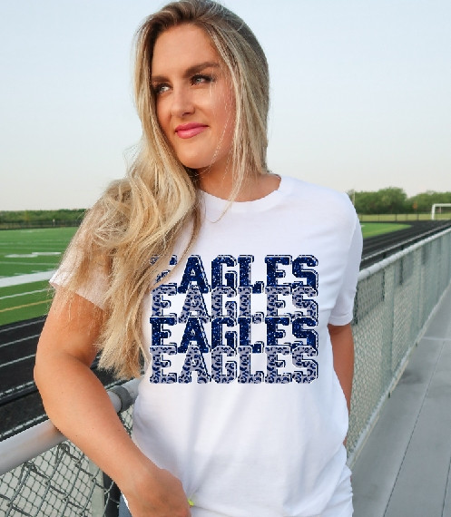 Eagles Royal Leopard Stacked DTF Heat Transfer, a white T-shirt with a bold blue eagle text design on the front, worn by a young woman outdoors near a sports field.