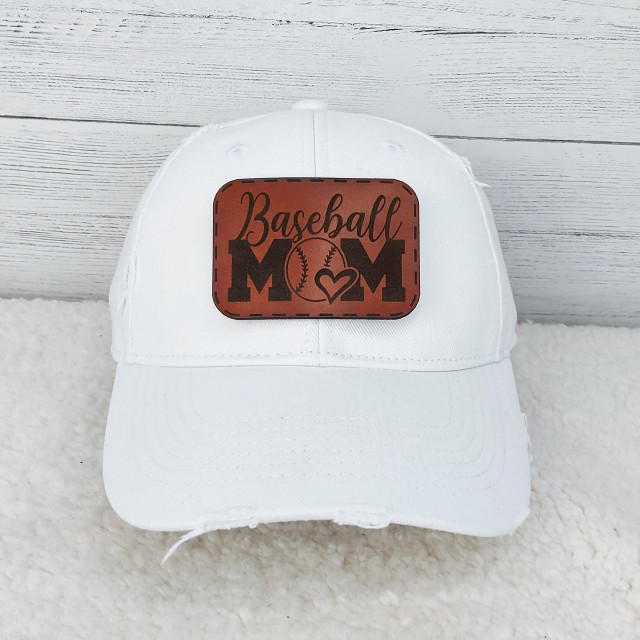 Baseball Mom Leather Hat Patch, white baseball cap with a brown leather patch featuring the words 'Baseball Mom' and a heart with a baseball design.