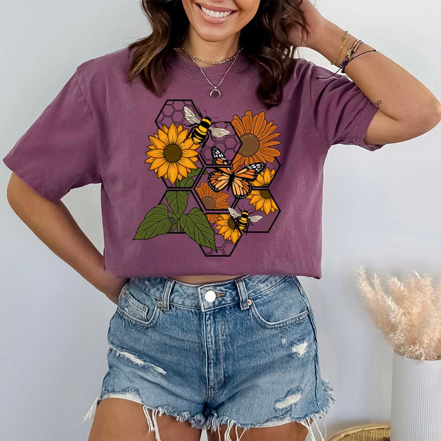 Bumblebee DTF Heat Transfer, colorful design featuring bees, sunflowers, and geometric honeycomb patterns on a woman wearing a purple T-shirt and denim shorts.