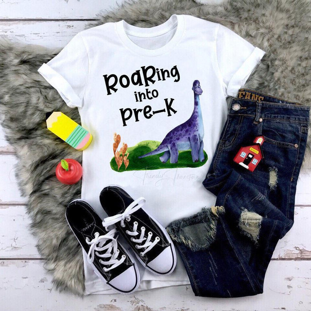 Roaring Into Pre-K Dinosaur Back To School Sublimation Transfer, white T-shirt with colorful dinosaur and playful text for preschoolers.