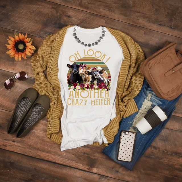 Oh Look Another Crazy Heifer sublimation transfer T-shirt, featuring cute cows with floral accents and retro rainbow background, displayed on a casual outfit with accessories.