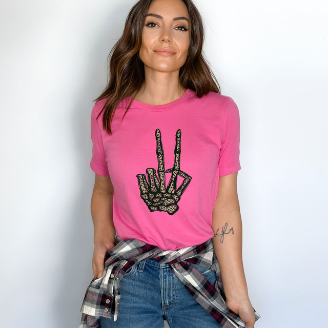 Leopard Peace Skeleton Hand DTF Heat Transfer, product showcasing a skeleton hand making a peace sign with leopard print details on a pink t-shirt.
