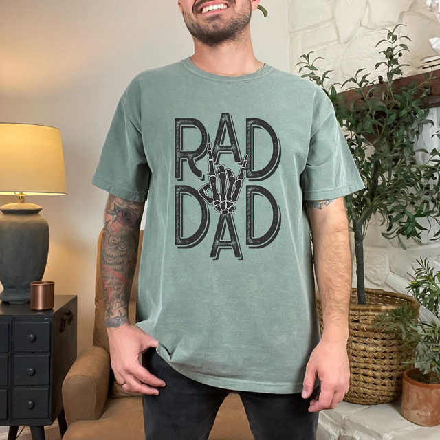 Rad Dad Skeleton Hand DTF Heat Transfer, skeleton hand making a rock on gesture between the words 'Rad Dad' on a men's T-shirt.