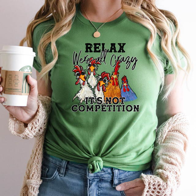 Relax Were All Crazy DTF Heat Transfer, colorful graphic design on a green T-shirt featuring humorous rooster illustrations with the phrase 'Relax We're All Crazy, It's Not Competition'.