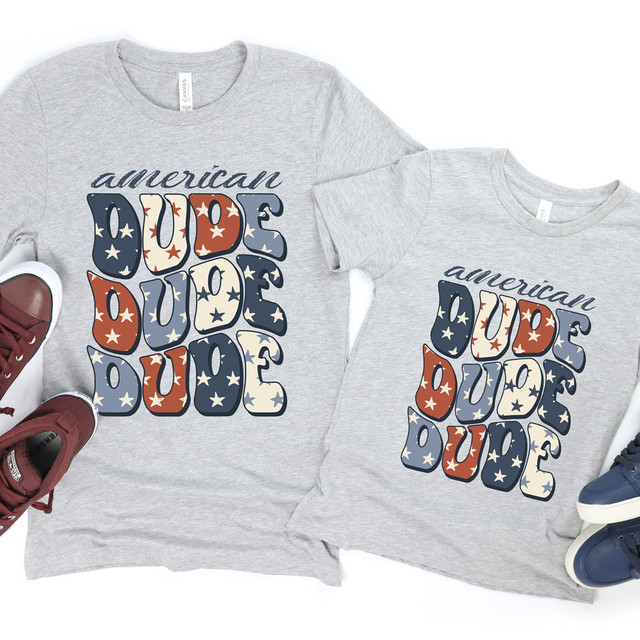 American Dude DTF Heat Transfer T-shirts, two gray T-shirts with patriotic-themed text design featuring stars and the words 'American Dude' in red, white, and blue colors.
