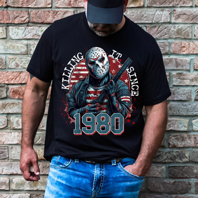 Killing It Since 1980 DTF Heat Transfer, graphic T-shirt featuring a masked figure holding a bat against a background of an American flag and the year 1980.