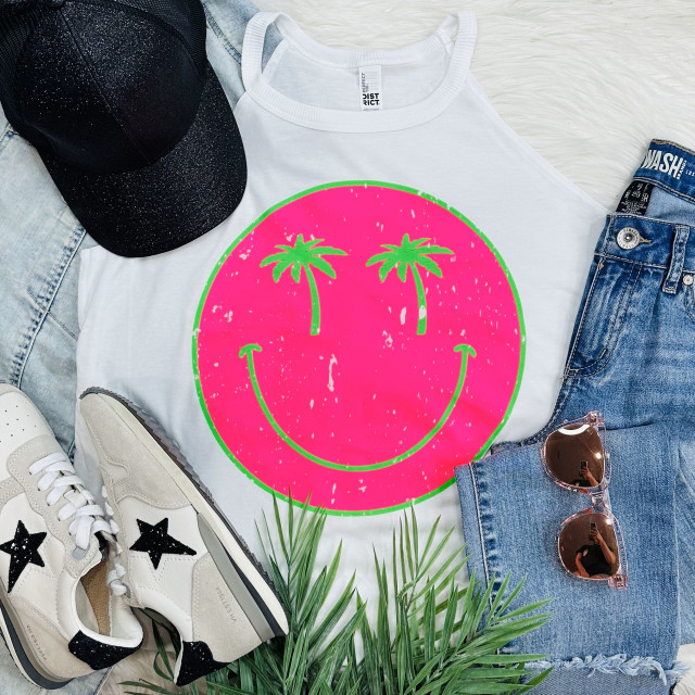 Palm Tree Face Neon Pink Screen Print Heat Transfer, vibrant neon pink smiley face with green palm trees as eyes on white T-shirt, sports accessories like black glitter cap, white sneakers with black star detail, blue denim shorts, orange sunglasses, and green palm plant nearby.