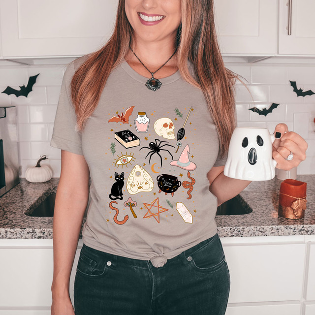 Halloween Doodles DTF Heat Transfer, a woman wearing a T-shirt adorned with various Halloween-themed illustrations including a skull, spider, witch hat, black cat, bat, cauldron, and other spooky symbols.