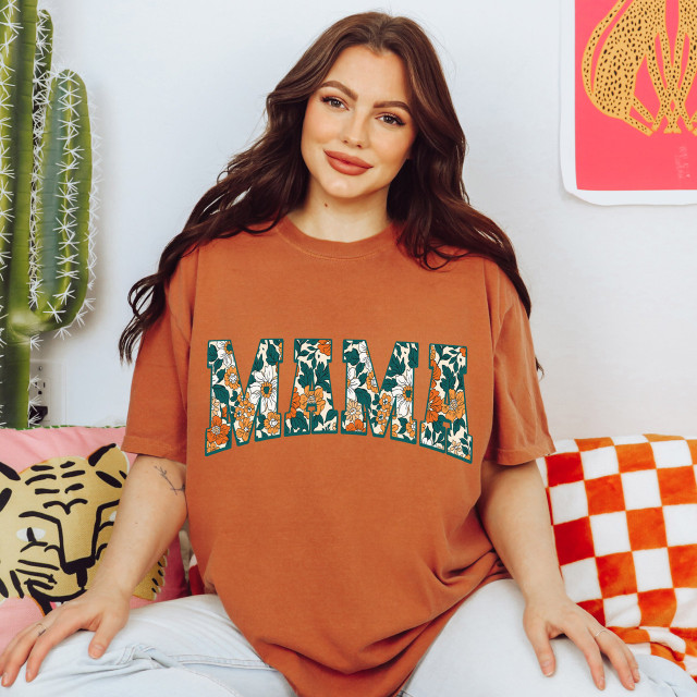 Fall Floral Mama DTF Heat Transfer, a colorful floral design spelling 'MAMA' on a woman's orange T-shirt.