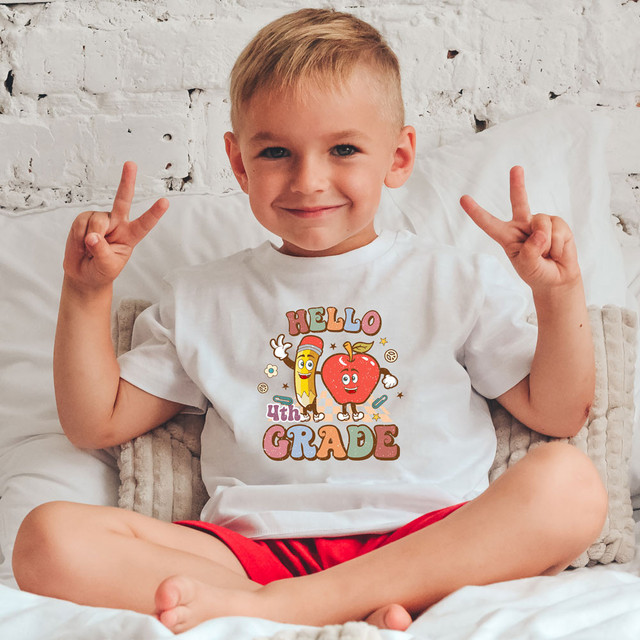 Hello 4th Grade Retro DTF Heat Transfer, a design featuring a smiling apple and pencil with the text 'Hello 4th Grade' on a boy's white t-shirt.