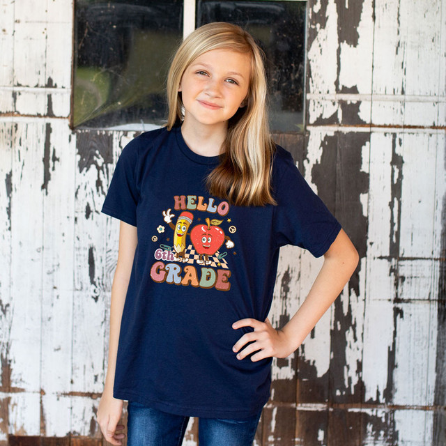 Hello 6th Grade Retro DTF Heat Transfer, front view of a girl wearing a navy T-shirt with colorful 6th Grade graphic design.