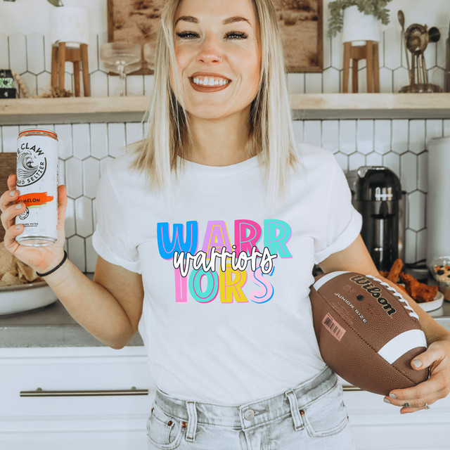 Warriors Colorful DTF Heat Transfer, vibrant multicolor design on a white t-shirt worn by smiling woman holding a can of sparkling water and a football.