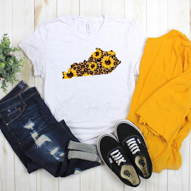 Kentucky Leopard Sunflower Sublimation Transfer, white T-shirt with sunflower and leopard print Kentucky state shape design, paired with distressed jeans, yellow jacket, and black Vans sneakers.