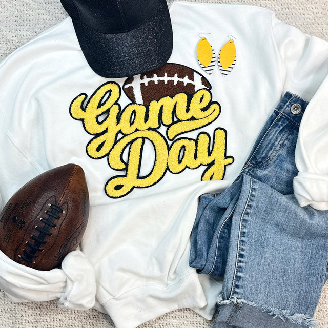 Yellow Game Day Football Chenille Patch, close-up of a white sweatshirt with a football and varsity letter patch, paired with denim shorts, a black cap, and a football.