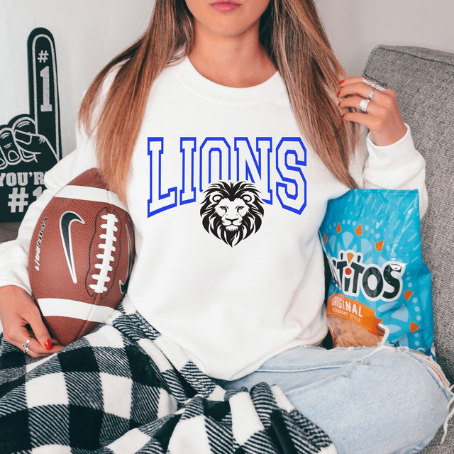 Lions Front Facing Mascot Custom Color Options DTF Heat Transfer on a women's sweatshirt with a lion face and bold blue text, sports-themed apparel for fans or teams.