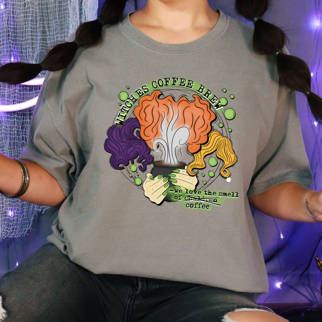 Witches Coffee Brew DTF Heat Transfer, colorful graphic design on a gray T-shirt featuring a steaming coffee mug with multicolored hair and the text 'Witches Coffee Brew' and 'we love the smell of witchen coffee'.
