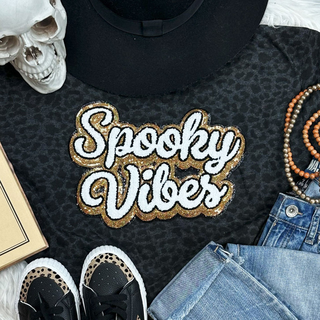 Spooky Vibes Sequins and Chenille Patch, decorative patch with the phrase 'Spooky Vibes' in white sequins outlined with gold and black beads, on a black fabric background with fashion accessories.