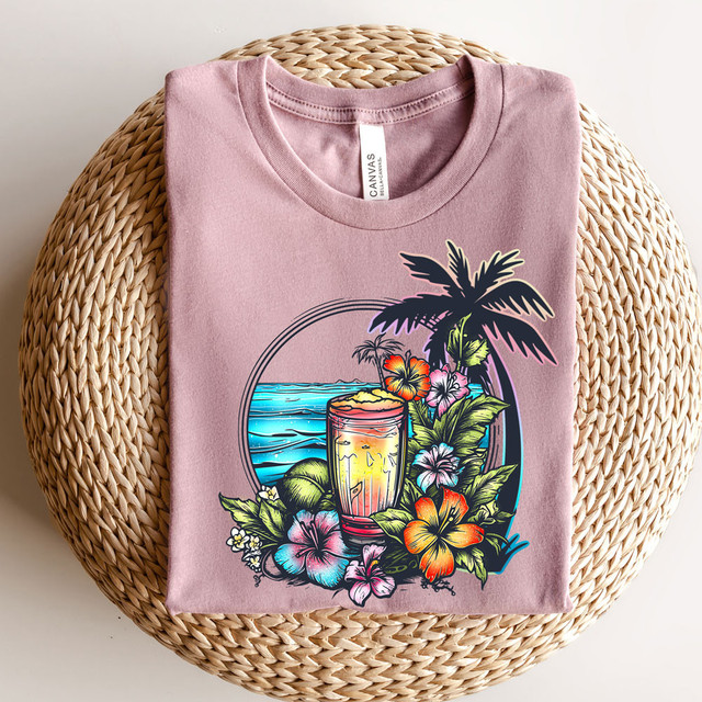 Tropical Drinks DTF Heat Transfer, vibrant colorful tropical beach scene on pink T-shirt featuring a cocktail, palm trees, ocean, and hibiscus flowers.