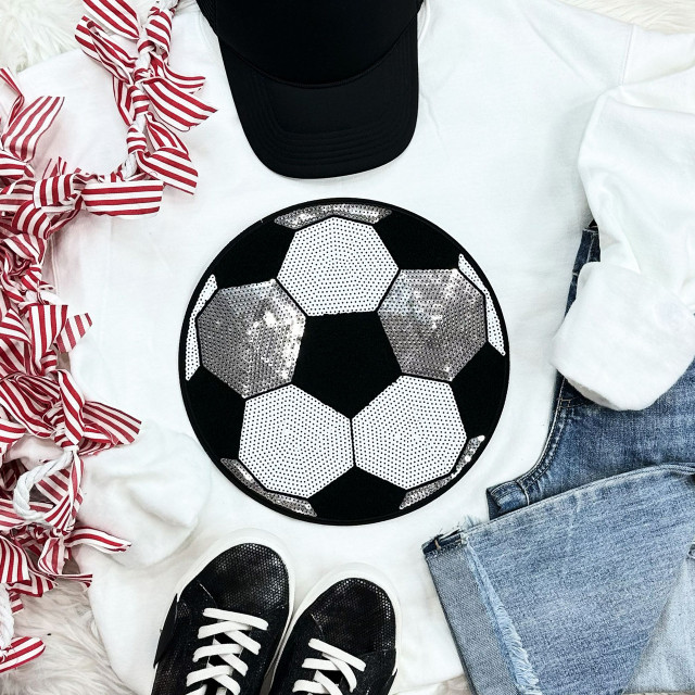 Sequins Soccer Patch Chenille Patch, decorative soccer ball patch with black, white, and silver sequins, on a flat lay of casual apparel and accessories including jeans, sneakers, a baseball cap, and a striped ribbon.