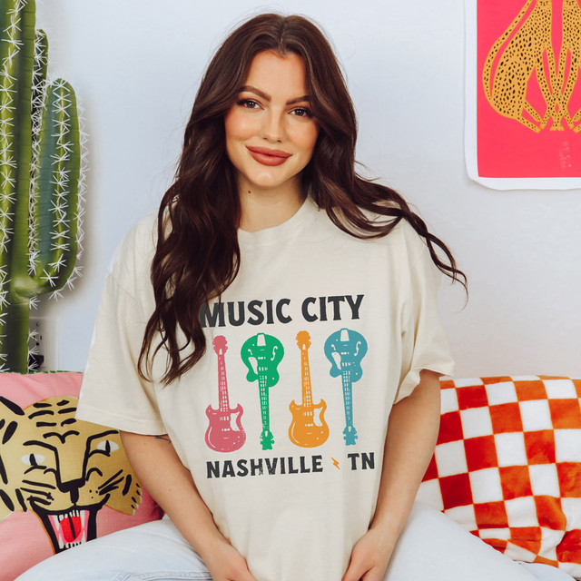Music City Guitars DTF Heat Transfer, colorful guitar illustration and Nashville TN text on a woman's t-shirt.