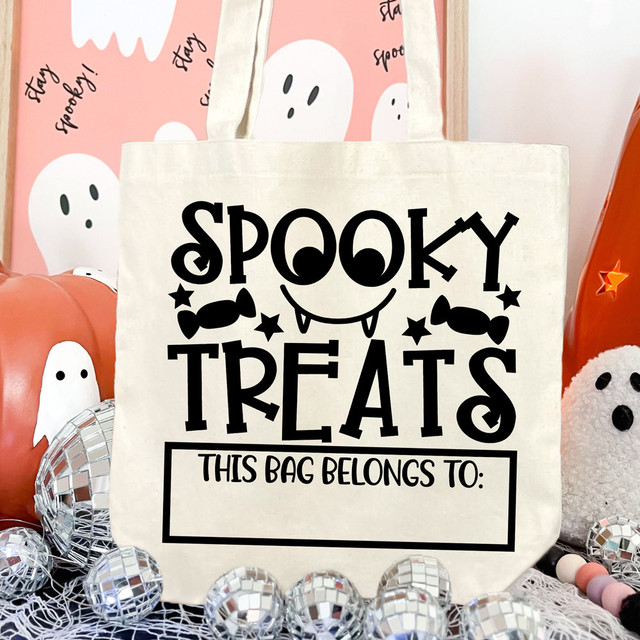 Spooky Treats DTF Heat Transfer, Halloween-themed tote bag with spooky face and candy design in black on a cream background, perfect for Halloween treat bags.