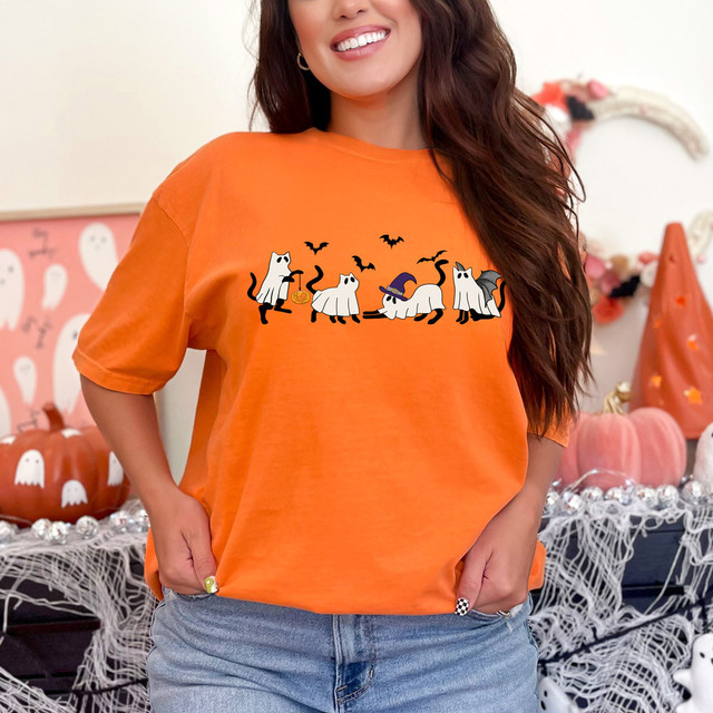 Cat Ghosts DTF Heat Transfer, Halloween-themed cat ghost design on an orange T-shirt worn by a smiling woman.