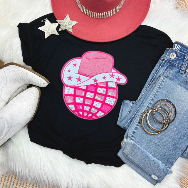 Cowboy Hat Sequin Disco Ball Chenille Patch, close-up view of a pink cowboy hat with a rhinestone band, on a black t-shirt featuring a sequin disco ball patch with a cowboy hat design, alongside denim jeans, white glove, and silver jewelry accessories.