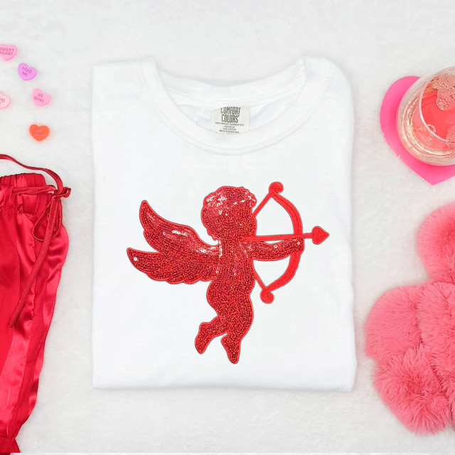Red Cupid Sequin Patch, a glittery red Cupid with wings, bow, and arrow on a white T-shirt, perfect for decorating clothing and accessories.