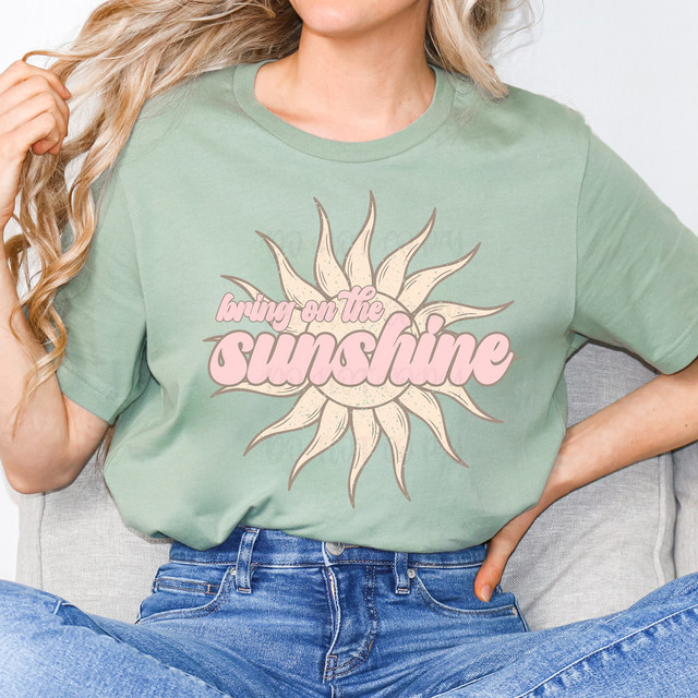 Bring On The Sunshine Boho DTF Heat Transfer, a graphic T-shirt with a sunburst design and the phrase 'bringing on the sunshine' in pink lettering.