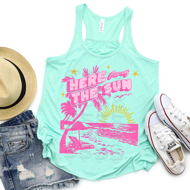 Here Comes The Sun Beach DTF Heat Transfer, a mint green tank top with pink sunset and palm tree graphic and text, accompanied by a straw hat, distressed denim shorts, and white sneakers for summer beachwear.