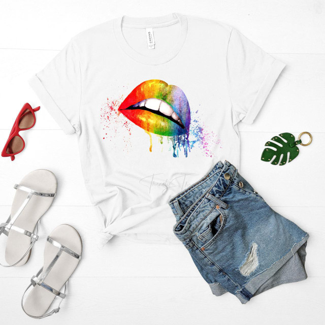 Rainbow watercolor lips sublimation transfer, printed on a white T-shirt with colorful splashes and drips, surrounded by fashion accessories like white sandals, red sunglasses, green monstera leaf keychain, and denim shorts.