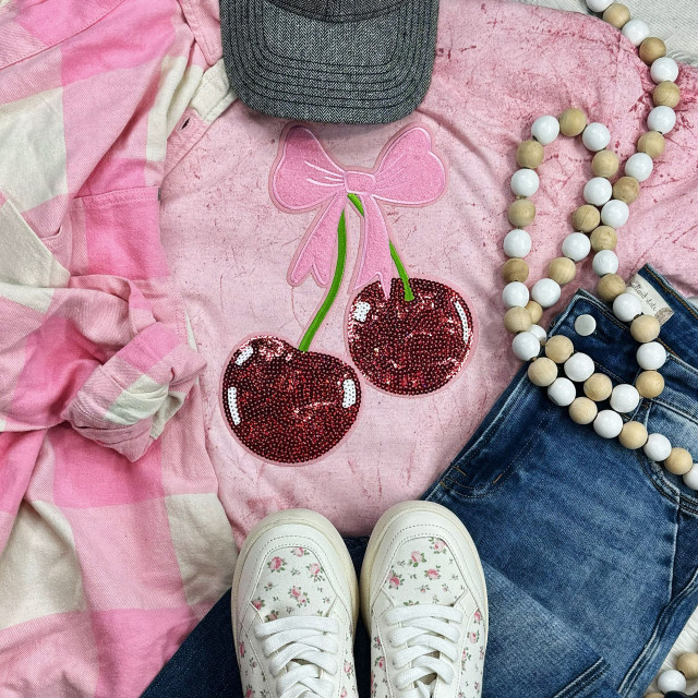 Double Cherries with Bow Chenille Sequin Patch, pink sweatshirt with cherry and bow applique, surrounded by a pink and white checkered shirt, blue jeans with a beaded necklace, and white floral sneakers.