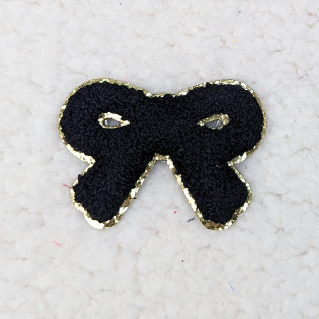 BLACK BOW Glitter Chenille HAT/POCKET Patch, black bow-shaped patch with glittery gold edges and chenille texture.