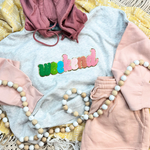 Weekend Chenille Patch, colorful chenille letter patch on a casual sweatshirt with pink and gray colors, surrounded by pastel pink shorts and beaded accessories.