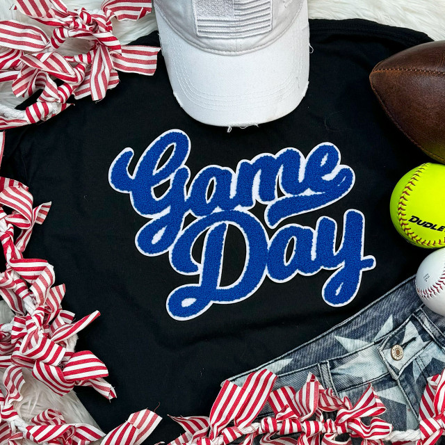 NO SPORT Royal Game Day White Backing Chenille Patch, image of a black t-shirt with blue chenille 'Game Day' lettering, surrounded by sports accessories including a white cap, football, softball, and red-and-white striped fabric loops.