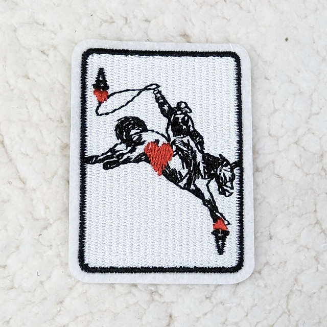 Rodeo ACE Embroidered HAT/POCKET Patch, embroidered patch featuring a figure holding a flag with a heart design, on a white background.