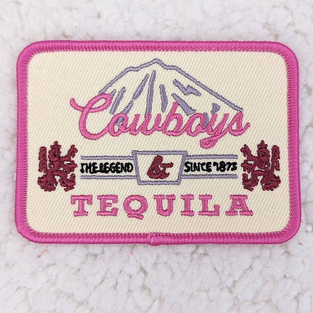 Cowboys & Tequila Embroidered HAT/POCKET Patch, embroidered patch featuring a pink and purple design with the text 'Cowboys & Tequila,' a mountain, lions, and the phrase 'The Legend Since 1873' on a cream background with pink border.