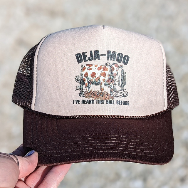 Deja-moo Hat/Pocket Screen Print Heat Transfer, a trucker cap with a white front panel featuring a cow illustration and the phrase 'I've heard this bull before'.