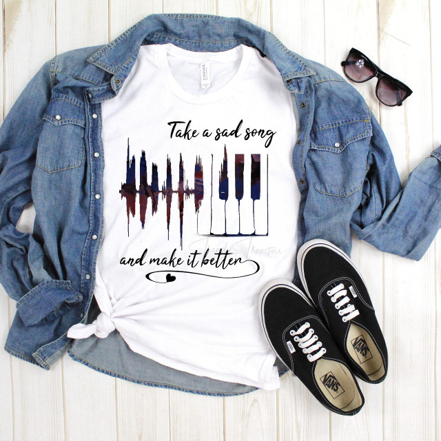 Take a sad song and make it better Beatles Fan Art Sublimation Transfer T-shirt with graphic of piano keyboard and sound wave design, paired with denim jacket, sunglasses, and Vans sneakers, apparel display on light wooden surface.