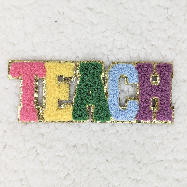 TEACH Chenille & Glitter Hat/Pocket Embroidered Patch, colorful embroidered patch spelling 'TEACH' with pink, yellow, green, blue, and purple chenille and glitter details on a white surface.
