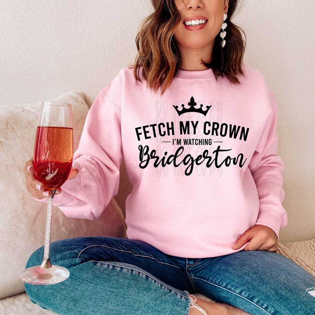 Fetch My Crown I'm Watching Bridgerton BLACK DTF Heat Transfer, product image of a woman wearing a pink sweatshirt with the text and crown design, holding a glass of rose wine.