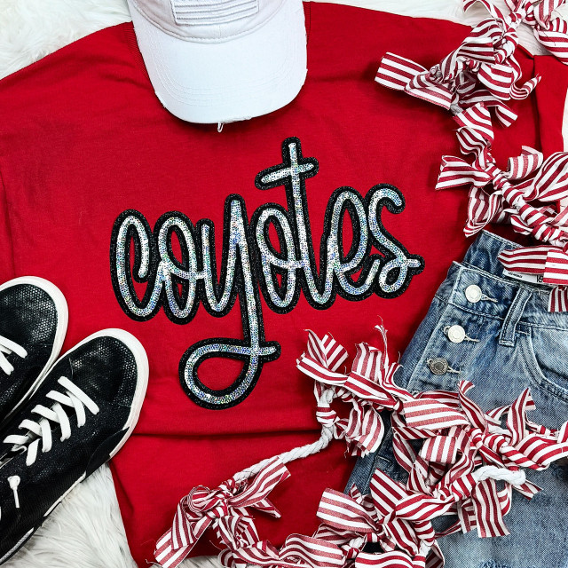 Coyotes Sequin Patch, a red T-shirt with a colorful sequin design of the brand name 'Coyotes' displayed flat among stylish sneakers, striped ribbon ties, and denim jeans in a flat lay fashion arrangement.