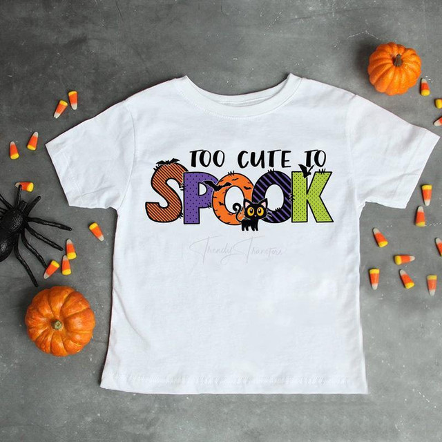 Too cute to spook halloween sublimation transfer T-shirt with colorful spooky design including a pumpkin and black cat on a gray background with small pumpkins, candy corn, and a spider for Halloween.
