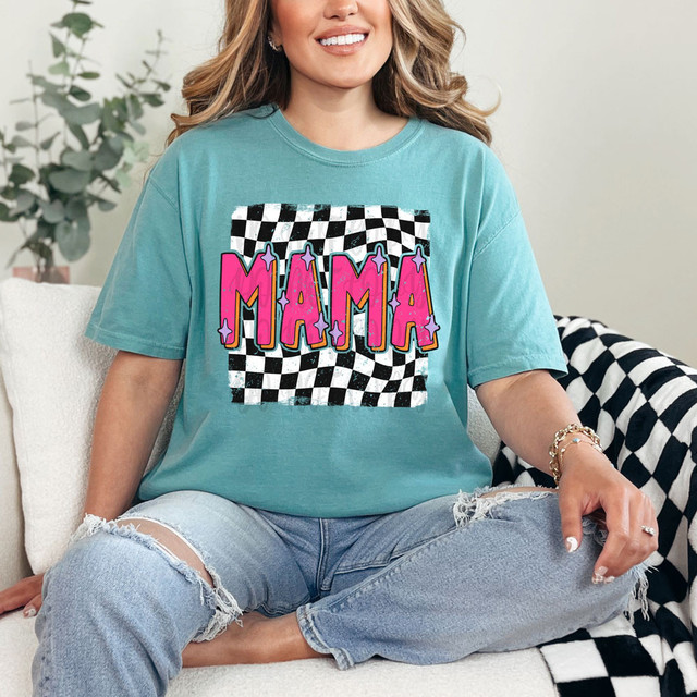 Mama Checker DTF Heat Transfer, colorful graphic design on a turquoise T-shirt worn by a smiling woman sitting on a white couch.