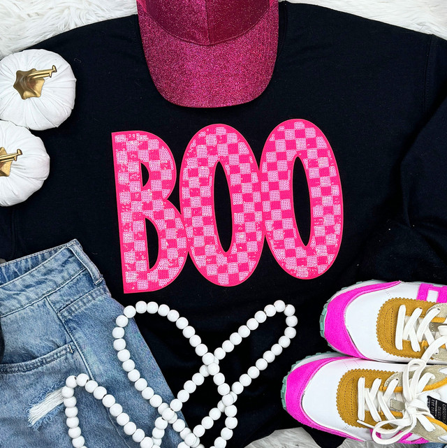 Checkered Pink BOO Sequin Patch, close-up of a pink checkered sequin patch spelling 'BOO' on a black t-shirt, with sneakers, denim shorts, white beads, and white pumpkins in the background.