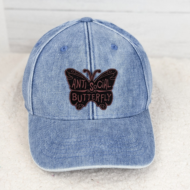 Antisocial Butterfly FAUX Leather Patch, blue denim baseball cap with a butterfly patch embroidered with the text 'Antisocial Butterfly' in black and pink.