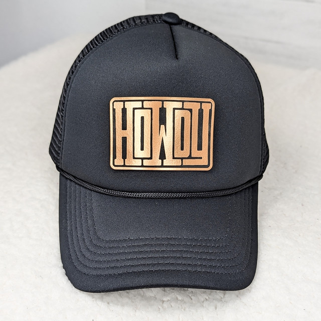 HOWDY FAUX Leather Patch, black trucker cap with a copper-colored patch displaying the 'HOWDY' logo in bold letters.