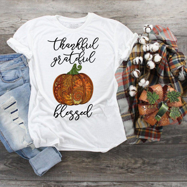 Thankful Grateful Blessed Paisley Ornate Fall Pumpkin Sublimation Transfer, an ornate pumpkin graphic with fall-themed paisley design on a white T-shirt, surrounded by denim, a plaid blanket, and fall decor.
