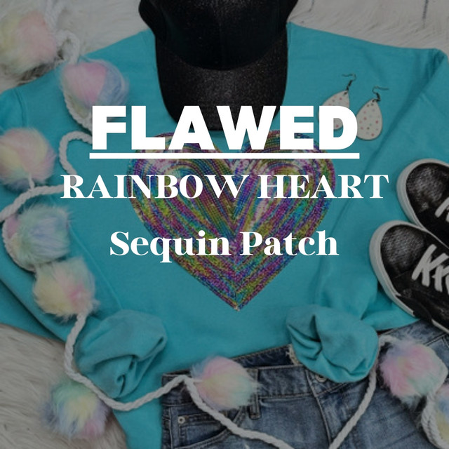 Flawed Rainbow Heart Sequin Patch, colorful heart-shaped sequin patch with a rainbow pattern, on a turquoise shirt surrounded by accessories and casual clothing items.